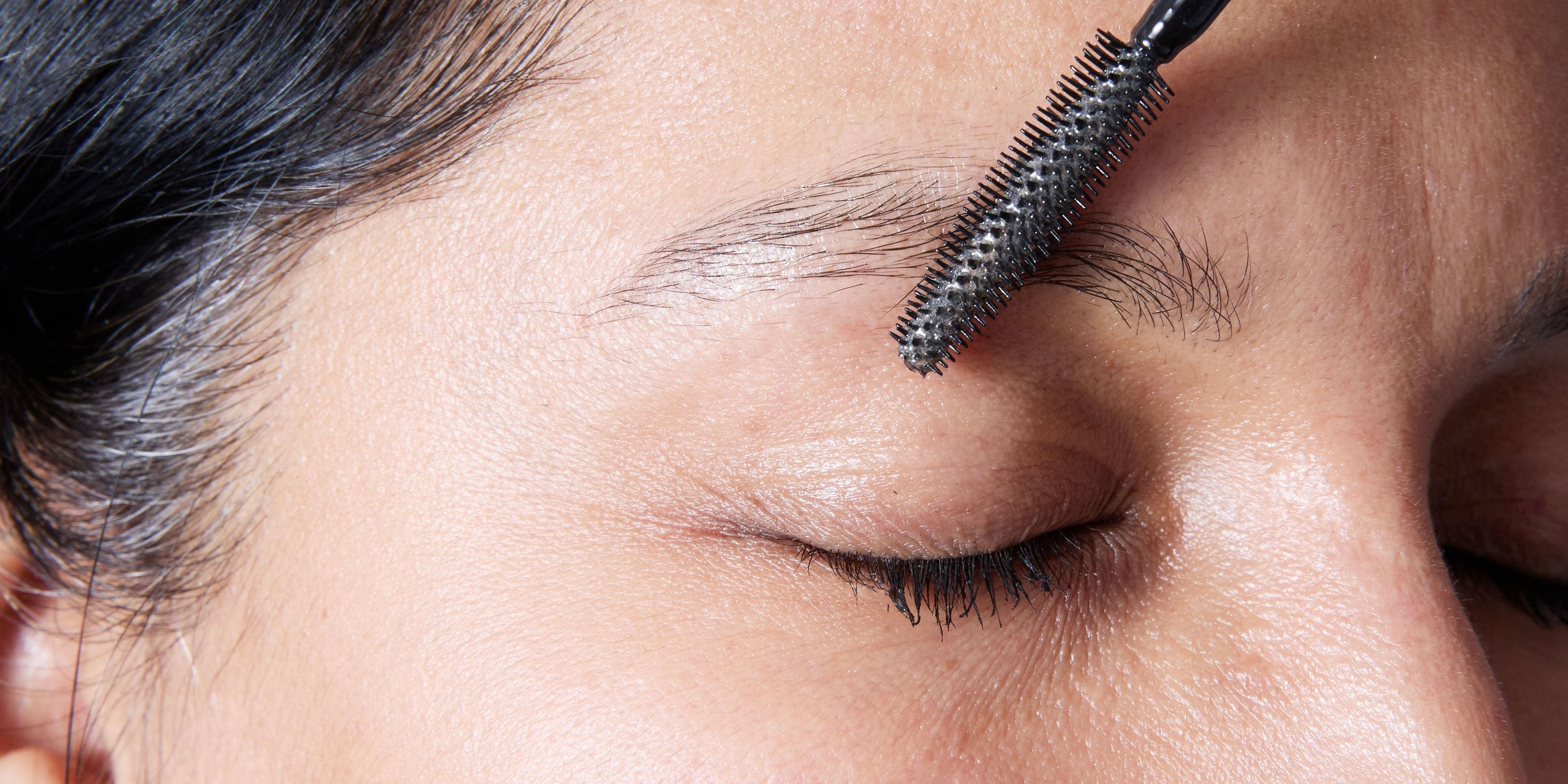 Lady applying castor oil to eye brows woth a brush