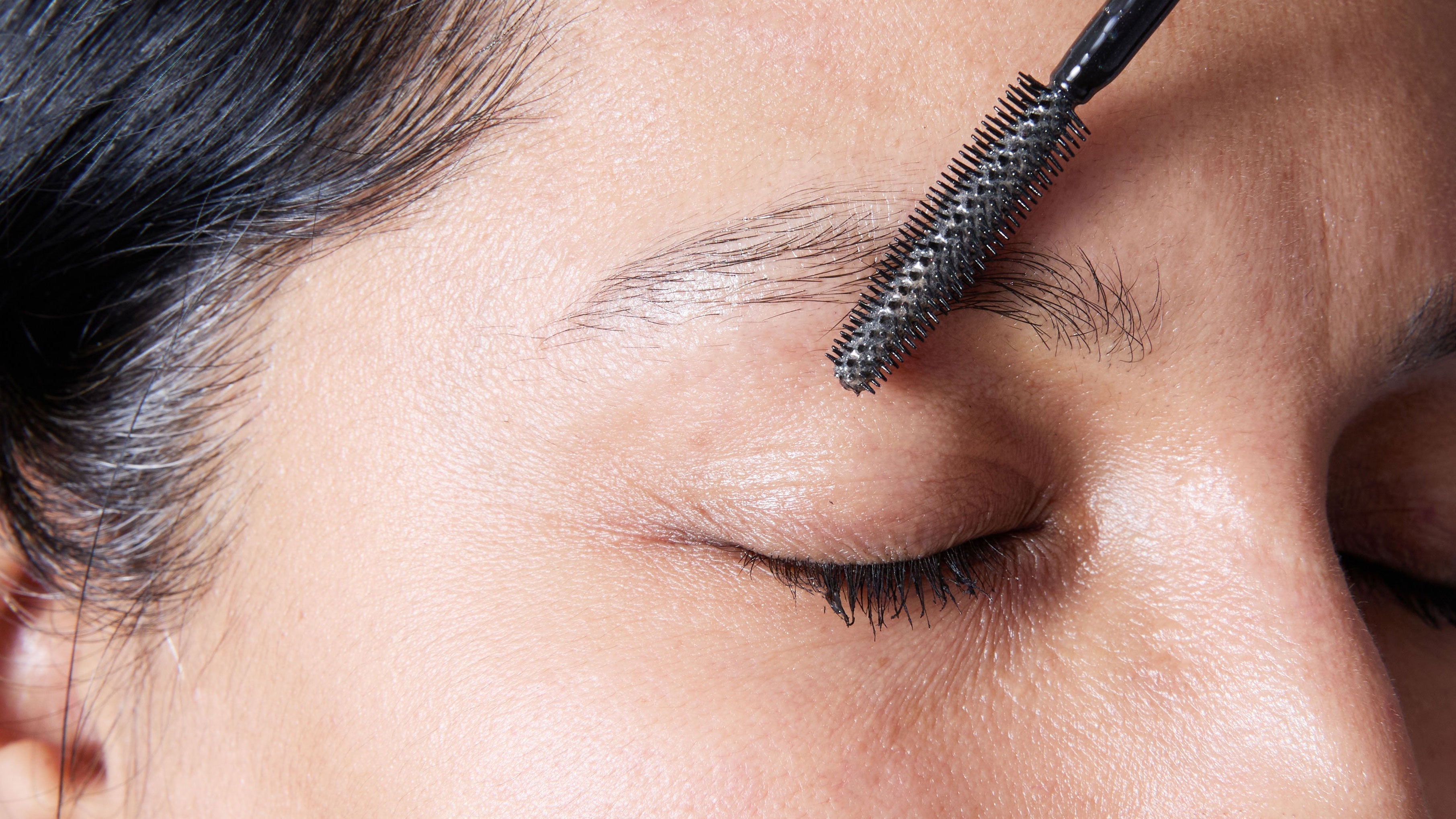 Lady applying castor oil to eye brows woth a brush