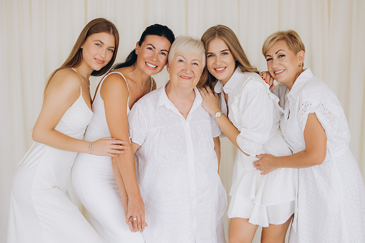 Women dressed in white from teenager to adult smiling