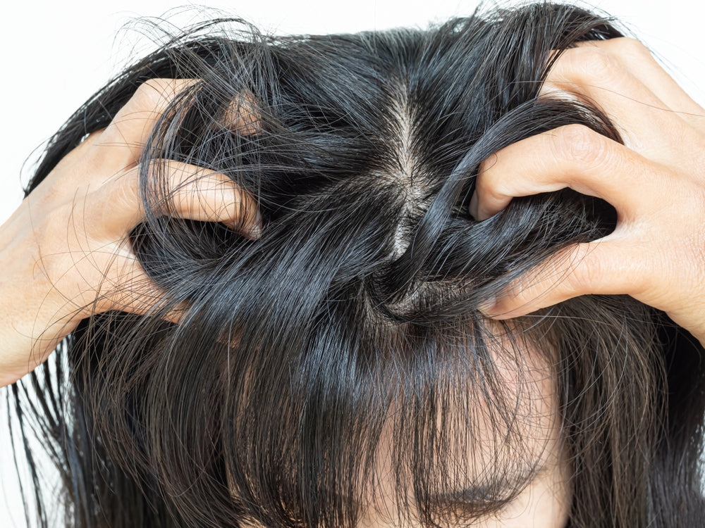 A lady in a white background, scratching her Itchy scalp