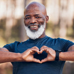 Man making a heart shape with his hands outdoors