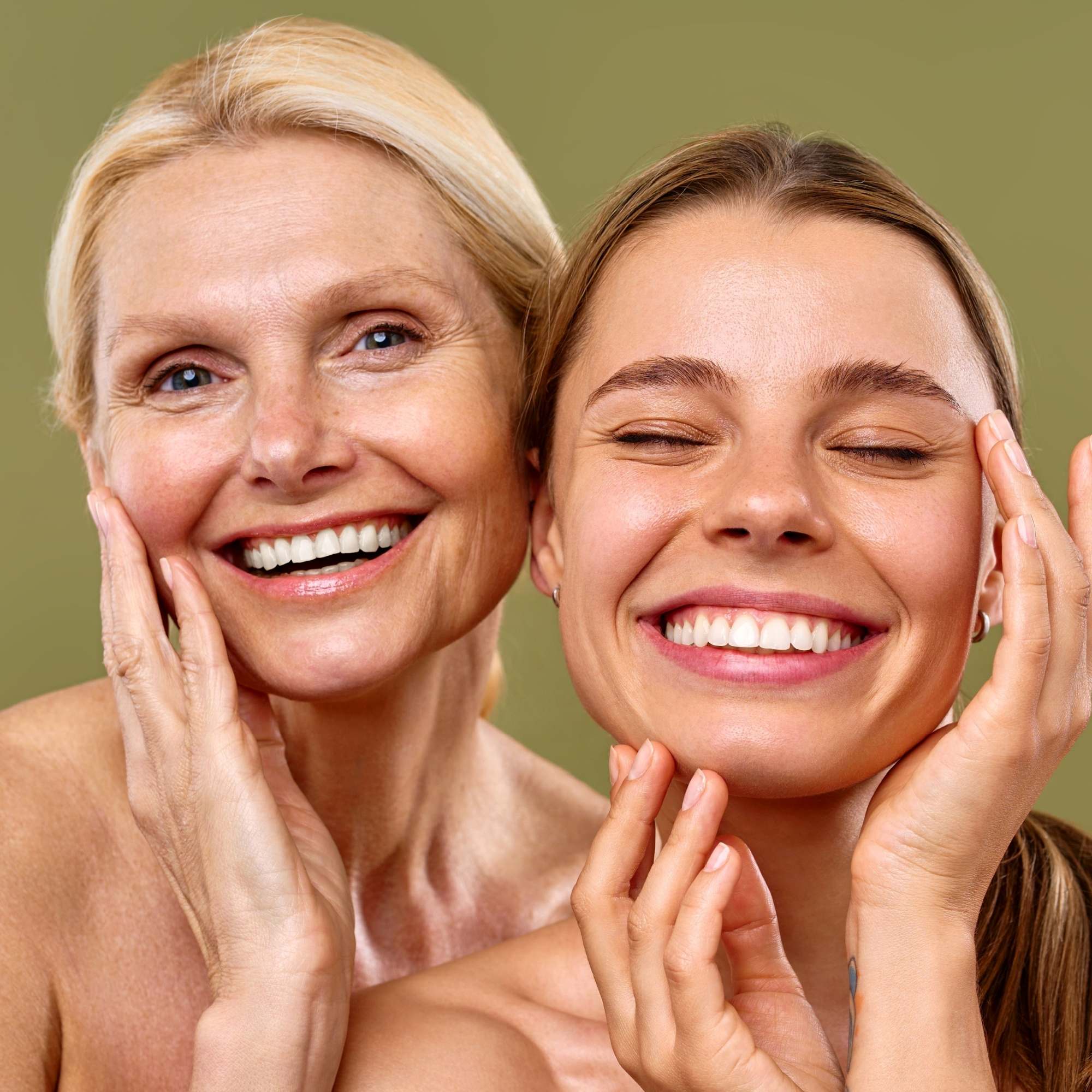 Two women touching their faces against a green background showing clear skin