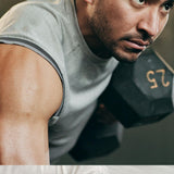 Man lifting a dumbbell with focus on his face and arm in a gym setting