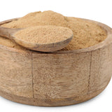 Wooden bowl filled with gokshura powder and a wooden spoon on a white background