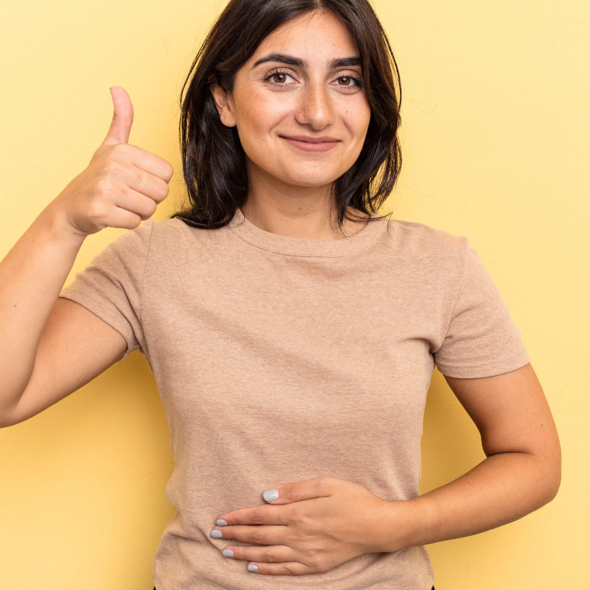 Woman giving a thumbs-up gesture against a yellow background