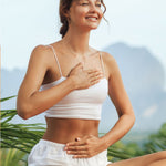 Woman wearing a white tank top and shorts with a blurred natural background