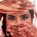 Woman with henna designs on her hands and face, wearing a traditional headscarf.