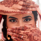 Woman with henna designs on her hands and face, wearing a traditional headscarf.