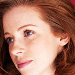 Close-up of a woman with red hair and blue eyes, just used Hibiscus Hair Mask