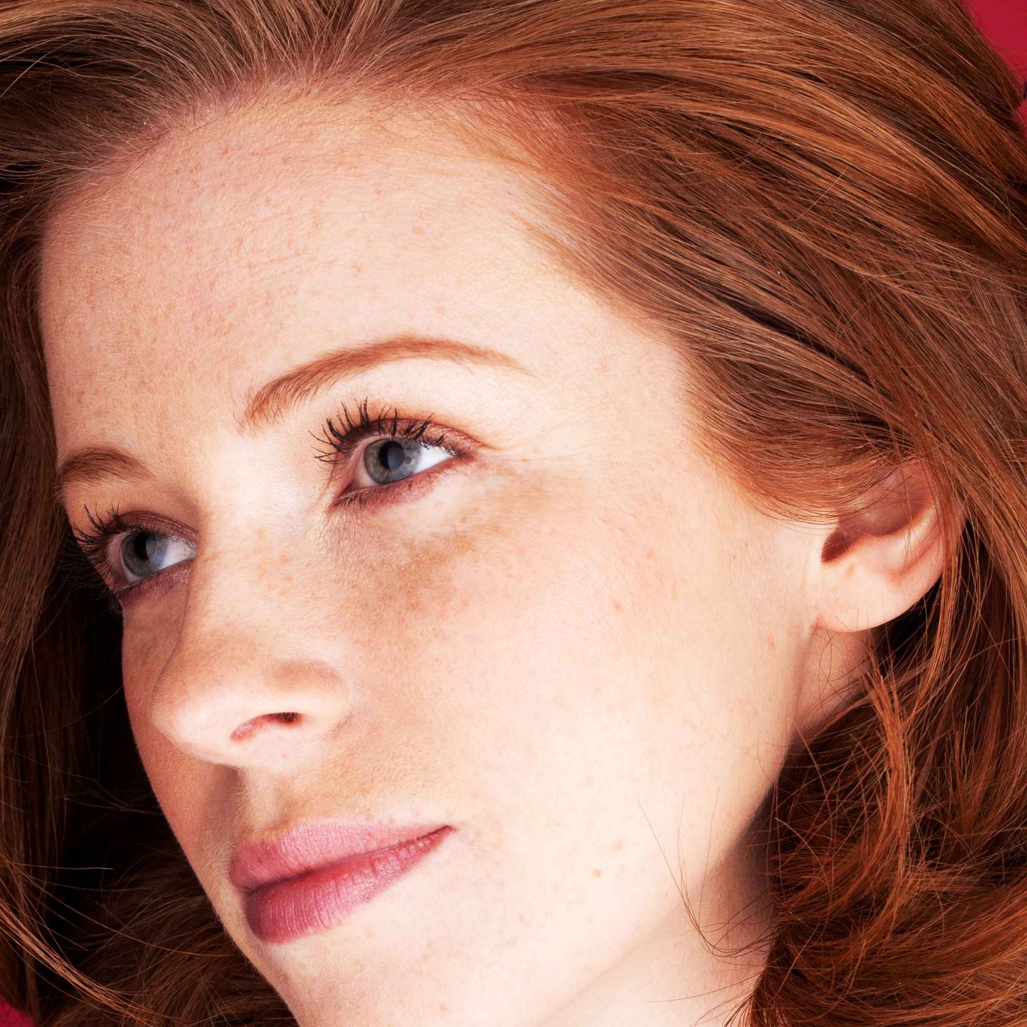 Close-up of a woman with red hair and blue eyes, just used Hibiscus Hair Mask
