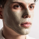 Close-up of a person with a Multani Mitti clay face mask on a neutral background