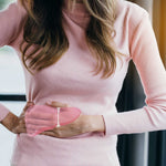 A women dressed in Pink, placing both hands on her Kidneys
