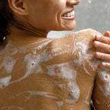 Person with soap suds on their back  using Ayumi Sandalwood Body Wash in a shower setting