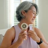 A woman having hot flushes and holding a fan to cool her down