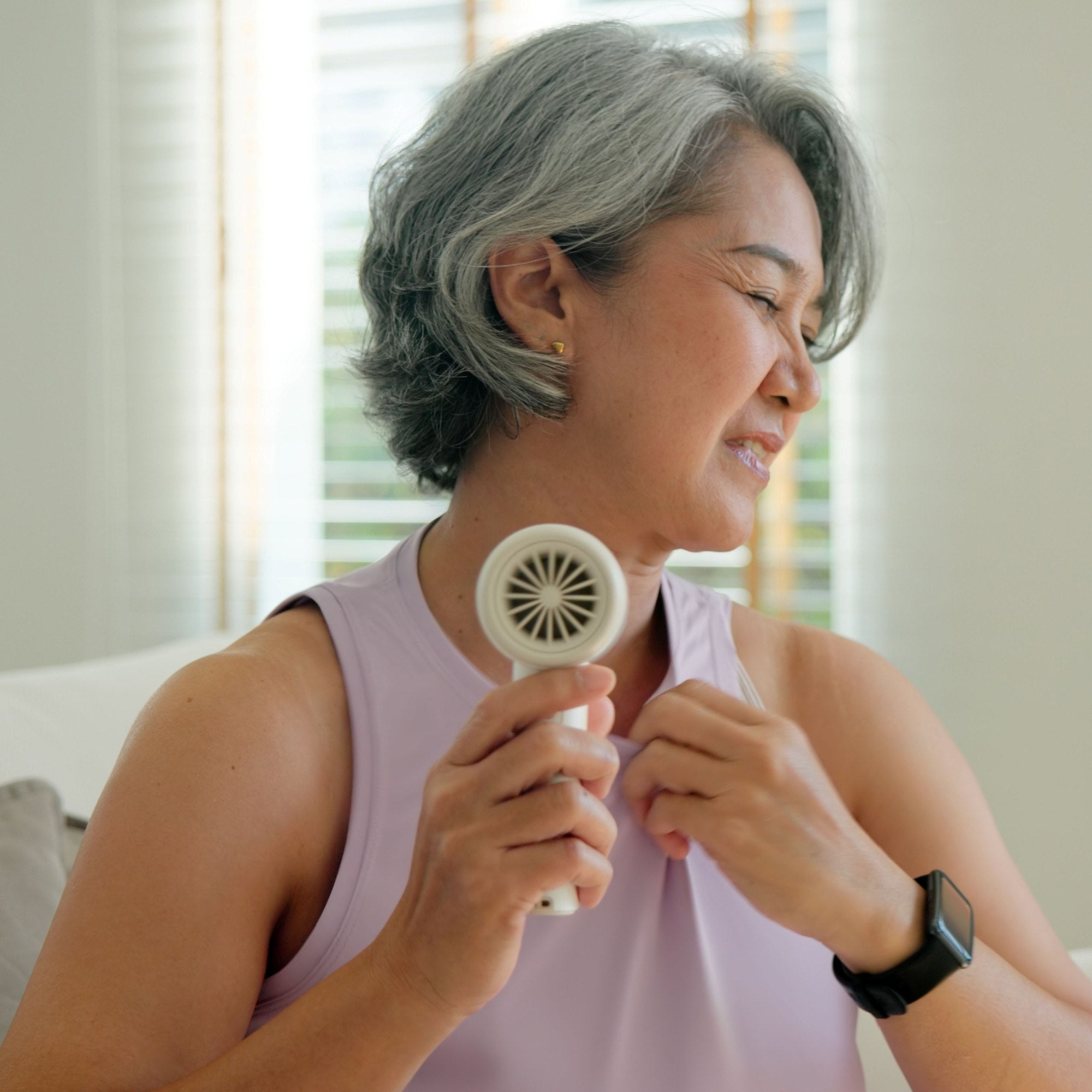 A woman having hot flushes and holding a fan to cool her down