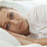 A woman in bed feeling pain from the symptoms of menopause