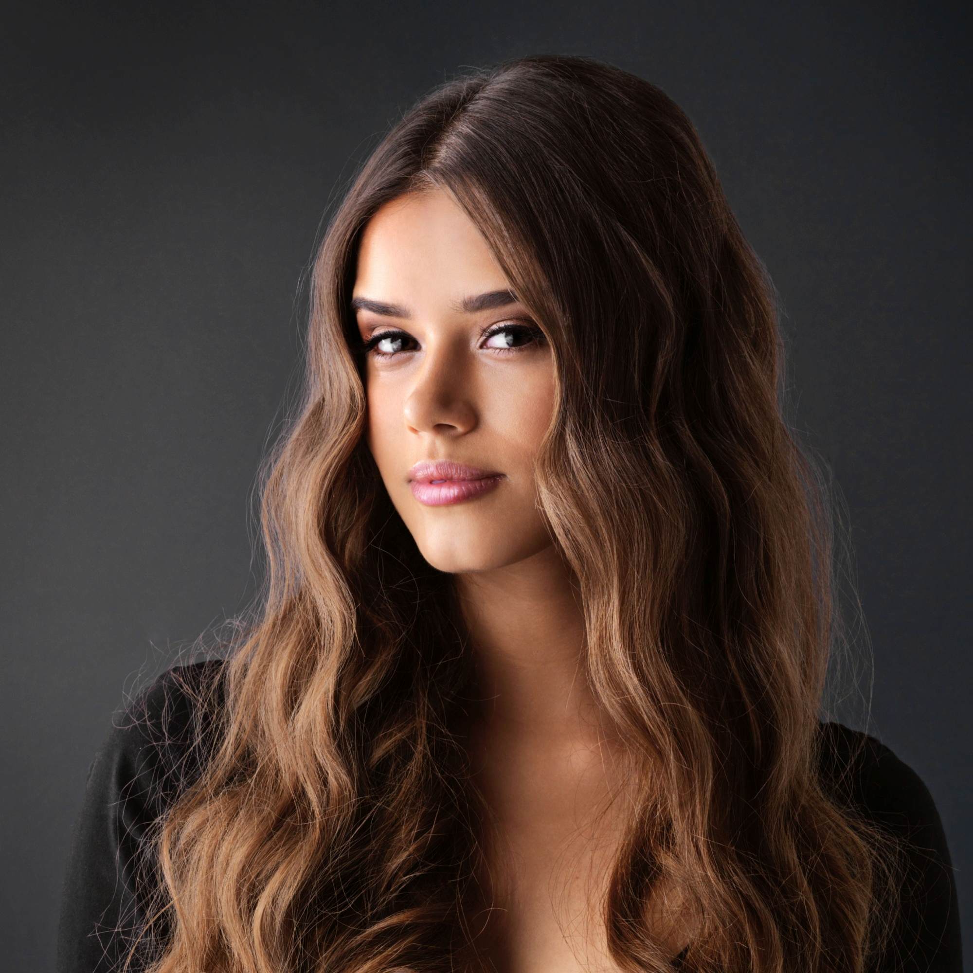 Woman with long, wavy hair against a dark background