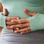 Close-up of two hands holding each other, one wearing a ring, against a blurred background.