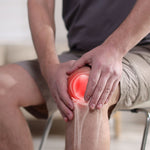 Person holding a knee with red highlighting indicating pain or injury.